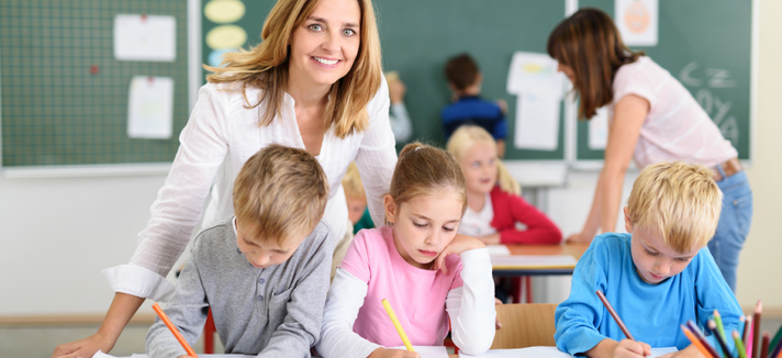 Freundliche Lehrerin mit Kindern in der Grundschule © adobe_contrastwerkstatt Freundliche Lehrerin mit Kindern in der Grundschule